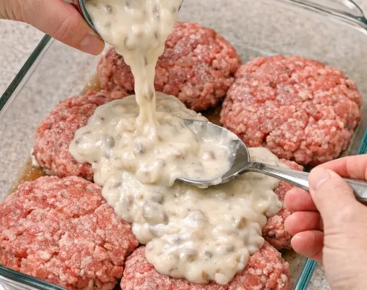 Pour cream of mushroom soup over raw ground beef patties, coupled with 2 ingredients, into a glass baking dish for a hearty supper that’s the one ev